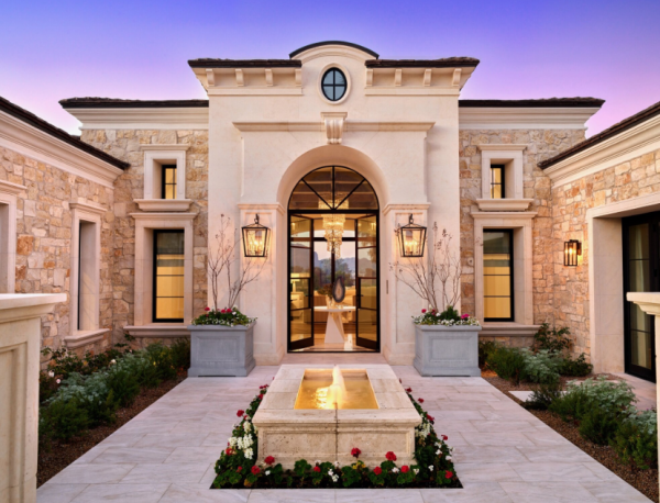 Desain rumah dengan kolom-kolom kokoh dan atap tinggi yang mencerminkan kemewahan